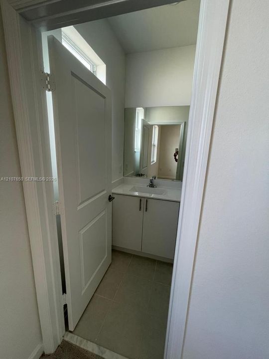 White vanity cabinet with an integrated rectangular basin, single-handle chrome faucet, large rectangular wall mirror, and neutral tile flooring