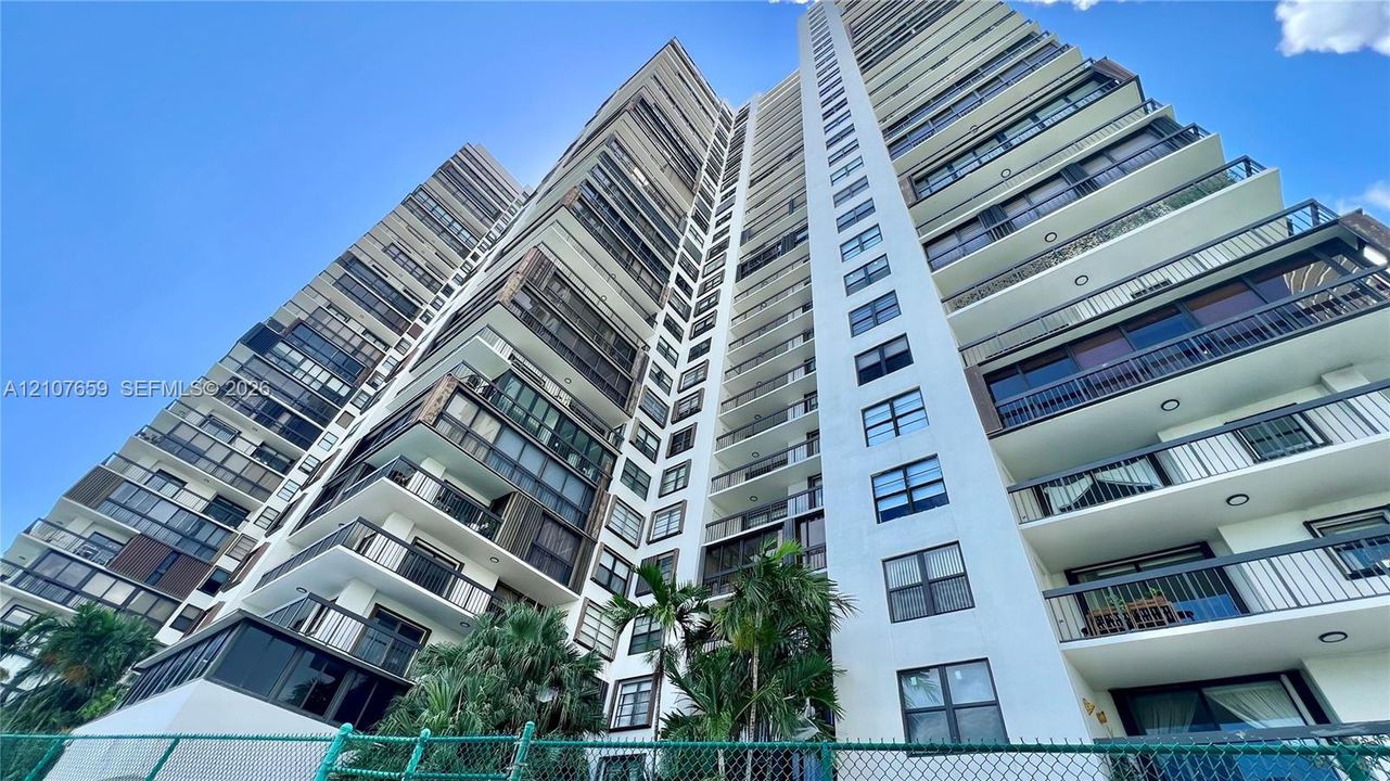 High-rise residential exterior featuring stacked private balconies, floor-to-ceiling glass windows, and reinforced concrete facade