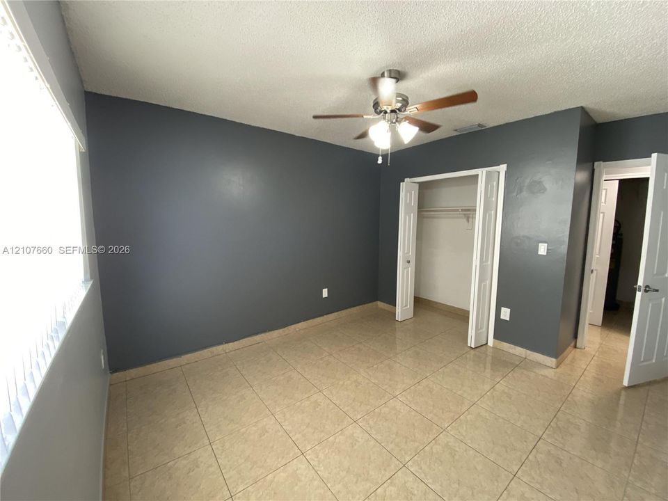 3rd Bedroom - Room featuring tile flooring, ceiling fan with integrated lighting, dual-panel closet doors, and recessed window treatments