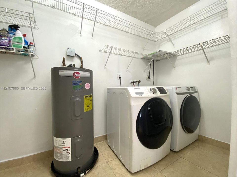Utility area featuring tile flooring, white wall-mounted wire shelving, and a dedicated water heater