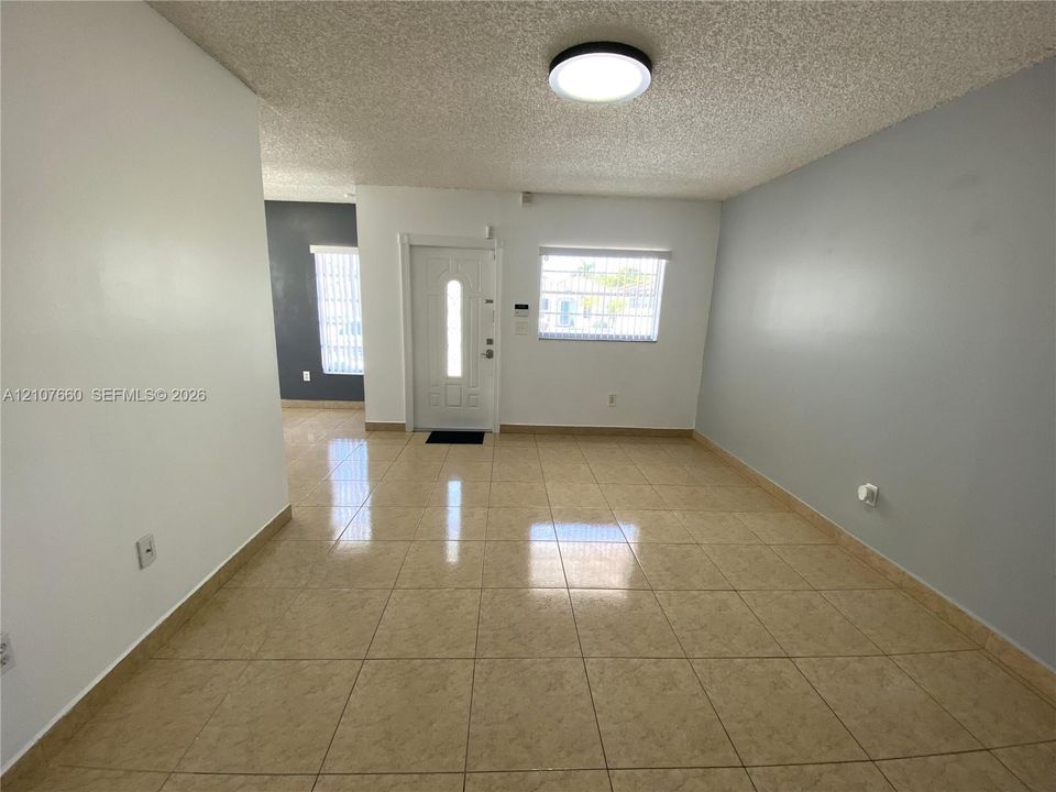 Tile flooring, neutral wall tones, multi-panel entry door with glass insert, and flush-mount ceiling lighting