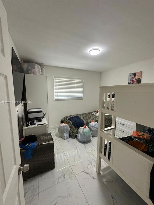 Large-format polished tile flooring, flush-mount ceiling lighting, and horizontal window blinds