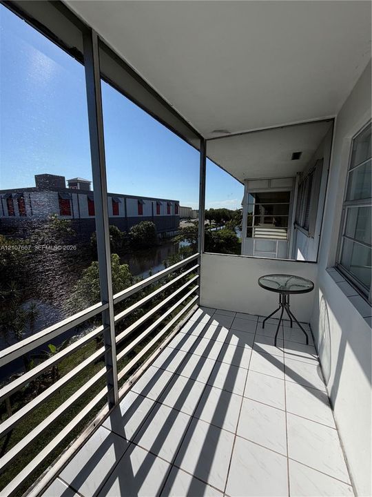 Screen-enclosed balcony featuring white ceramic tile flooring and metal railings
