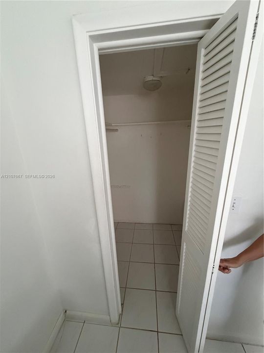 Storage area featuring louvered closet doors, ceramic tile flooring, and integrated overhead lighting