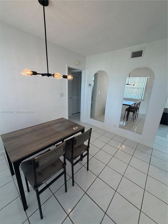 Tile flooring, arched wall mirrors, and a multi-bulb linear pendant light fixture