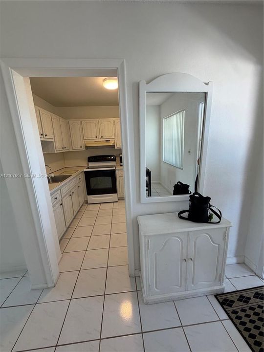 Kitchen featuring white cabinetry, an integrated range, a stainless steel sink, and light-toned tile flooring
