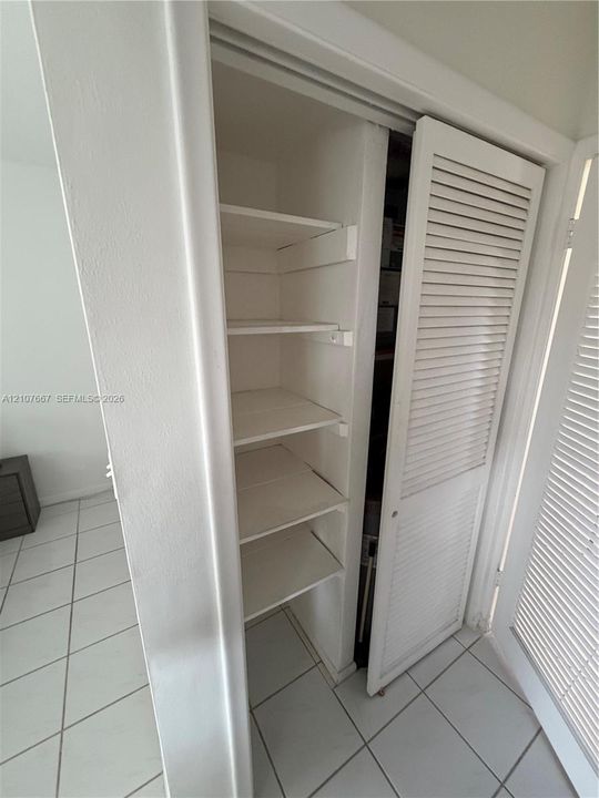 Built-in storage closet featuring louvered bi-fold doors and integrated shelving