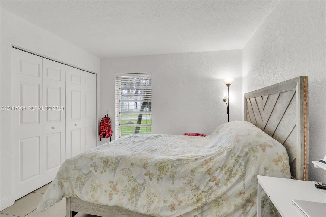 Room featuring white walls, large multi-panel closet doors, and a rectangular window with horizontal blinds