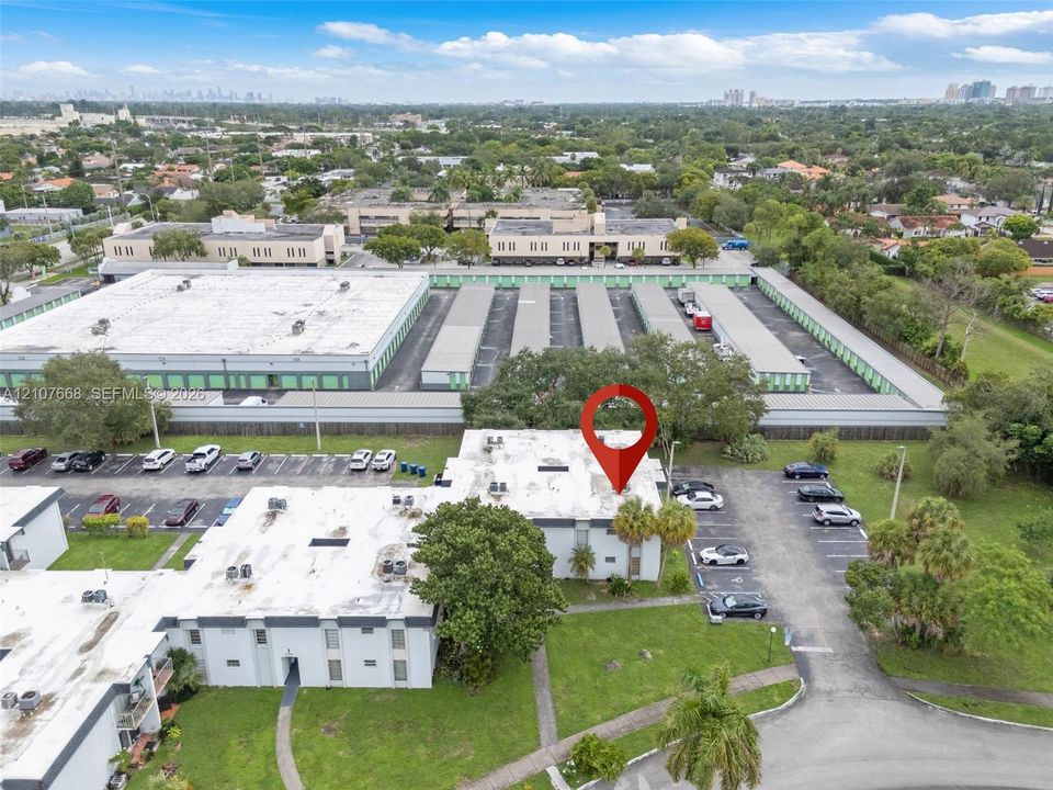 Aerial perspective of multi-level building with white exterior walls, flat roof system, dedicated surface parking, and manicured landscaping