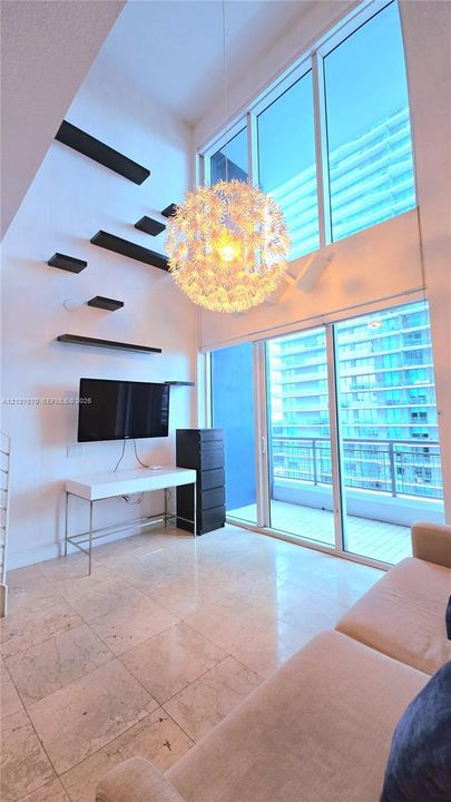 Double-height floor-to-ceiling windows, polished stone flooring, architectural floating wall shelves, and an oversized decorative pendant light fixture