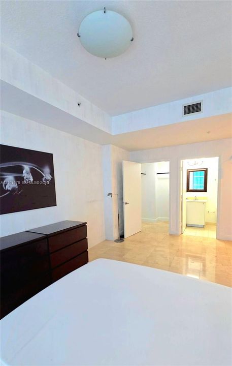 Stone flooring, tray ceiling with recessed lighting, and built-in closet storage