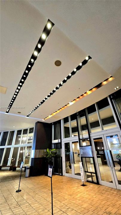 Entrance featuring recessed linear ceiling lighting, expansive floor-to-ceiling glass paneling, and stone tile flooring