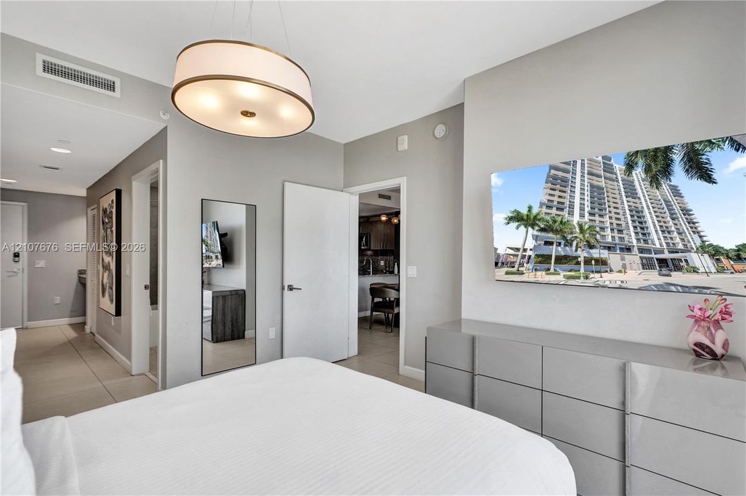 Neutral-toned interior featuring large-format tile flooring, recessed lighting, and a circular drum pendant light fixture