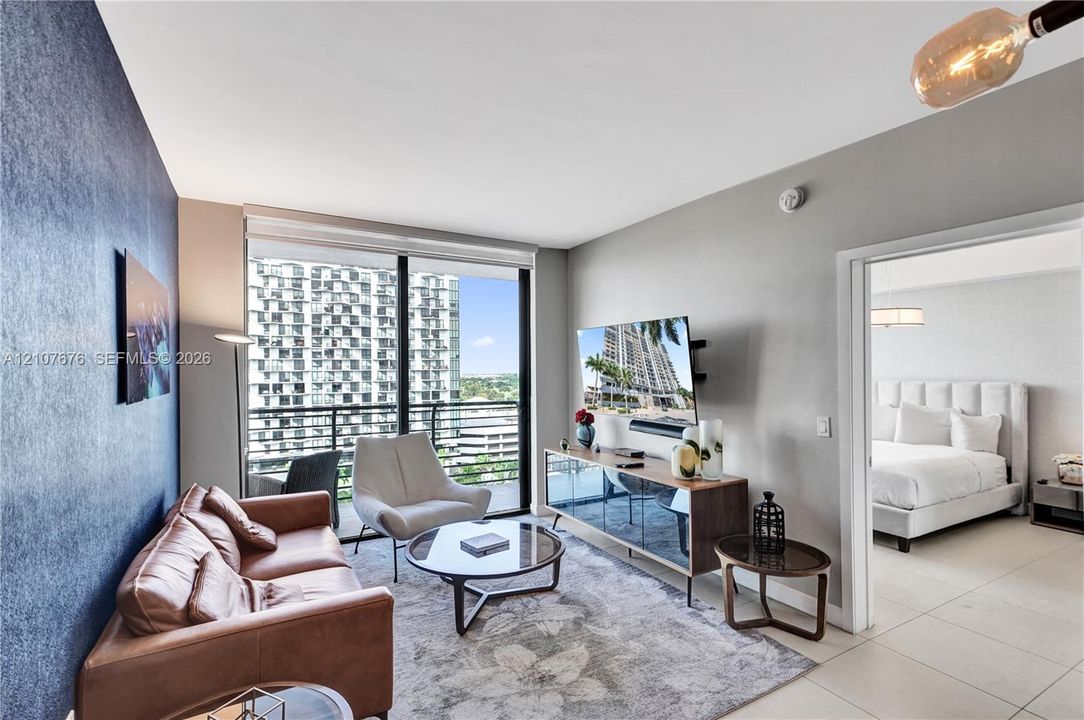 Floor-to-ceiling windows with balcony access, ceramic tile flooring, and accent wall