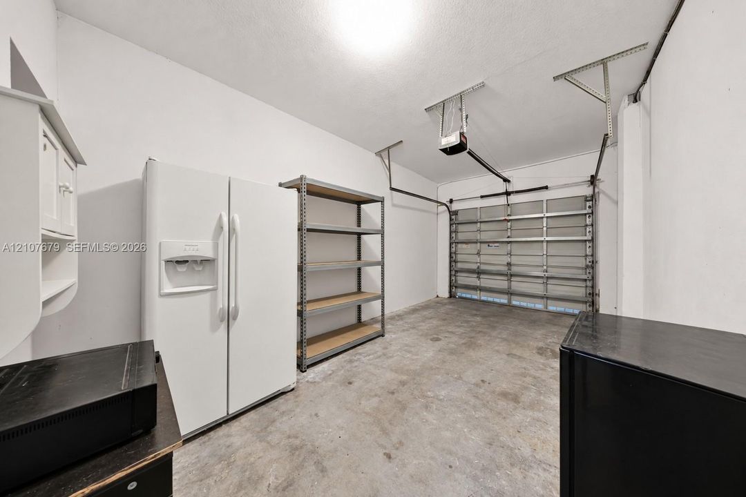 Garage space featuring an automatic overhead door opener, concrete flooring, and built-in wall-mounted cabinetry