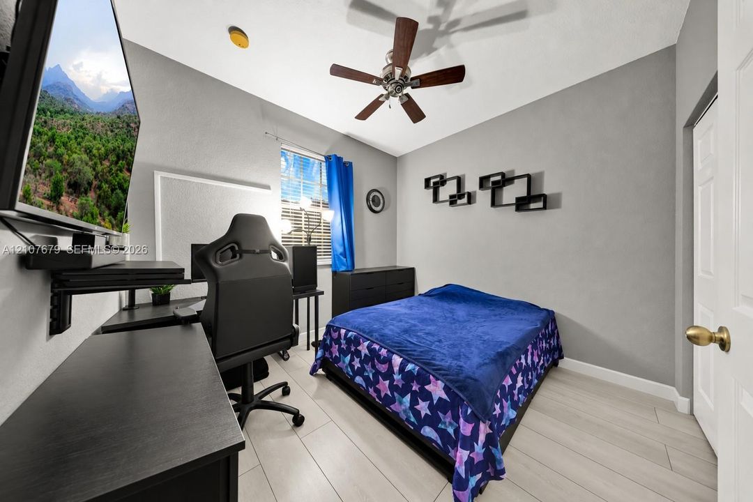 Room featuring wood-finish flooring, a multi-blade ceiling fan, and a single-pane window