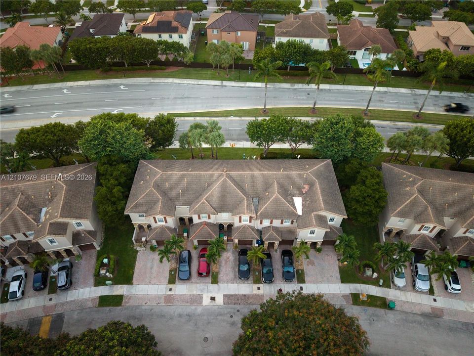 Aerial view of multi-unit residential property featuring a multi-pitched tile roof, paver driveways, and mature landscaping