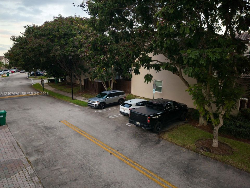 Exterior featuring designated surface parking, paved street access, and mature canopy trees
