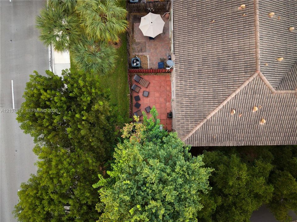 Outdoor space featuring a paved patio, perimeter fencing, and mature trees
