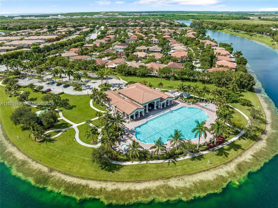 Waterfront community facility featuring a swimming pool, spa, paved walking paths, manicured landscaping, and a multi-purpose building with a tile roof