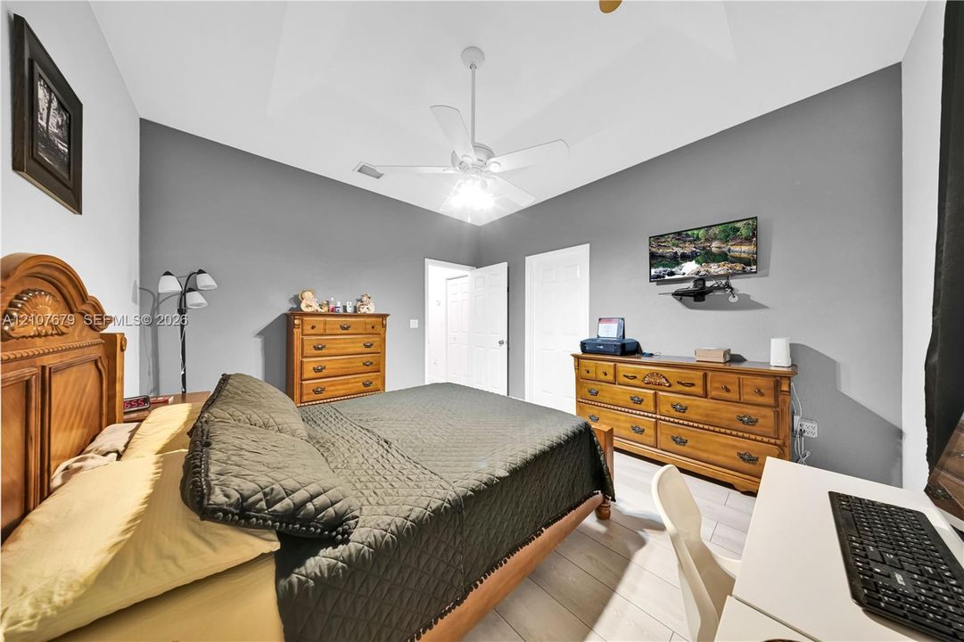 Vaulted ceiling featuring a central white ceiling fan with integrated lighting, paired with light-toned wood-finish flooring