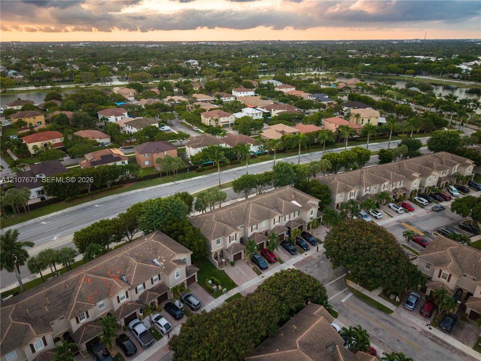 Aerial perspective of a multi-unit residential community featuring pitched tile roofs, paved driveways, and mature landscaping