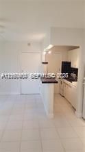 Kitchen featuring white cabinetry, dark contrasting countertops, a breakfast bar, and light-toned tile flooring