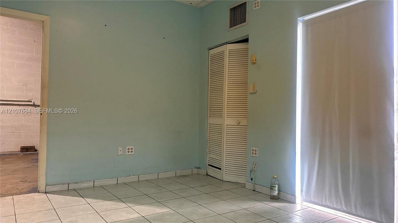 Ceramic tile flooring, bi-fold louvered closet doors, and a glass-panel door