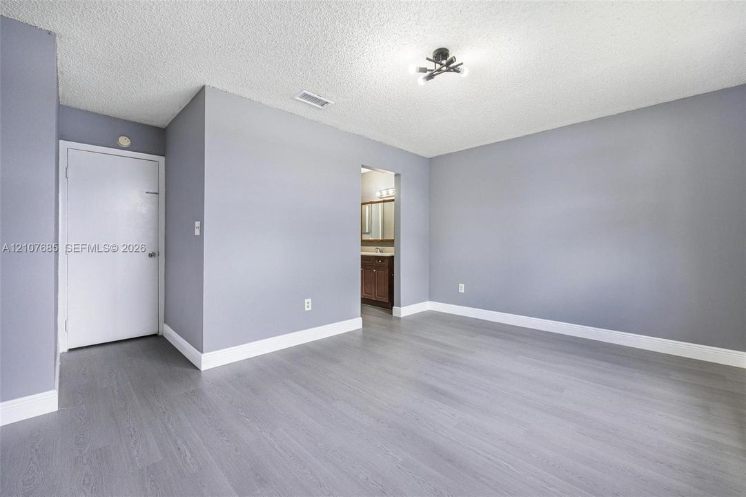 Room featuring wood-finish flooring, neutral gray wall paint, and multi-light flush mount ceiling fixture