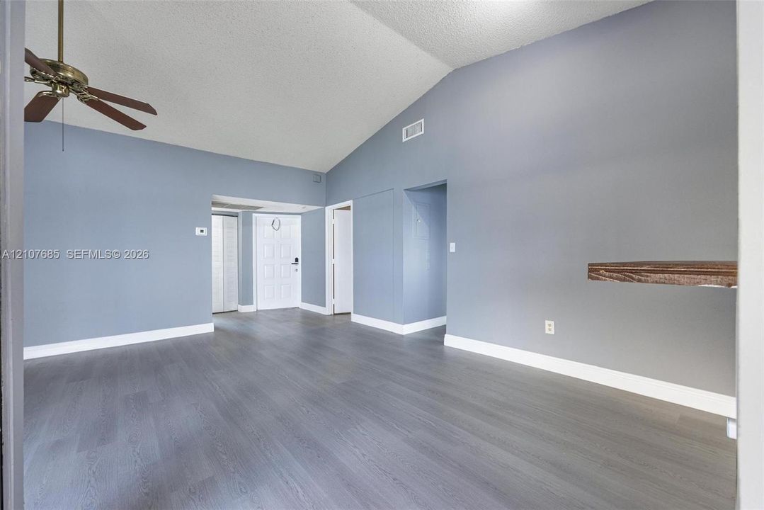 Vaulted ceilings, wood-finish flooring, and a ceiling fan with integrated lighting