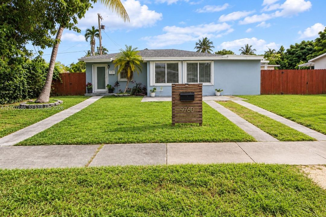 Single-story exterior featuring light-toned masonry, a horizontal wood-slat mailbox pedestal, dual-pane windows, and a paved concrete driveway