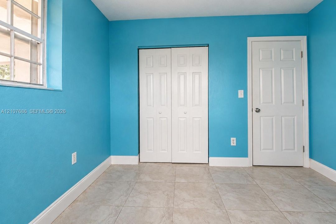 Interior room featuring tile flooring, a multi-pane window, and a white six-panel closet door