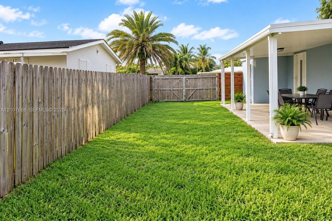 Fenced backyard featuring a manicured lawn, a covered concrete patio, and vertical wood privacy fencing