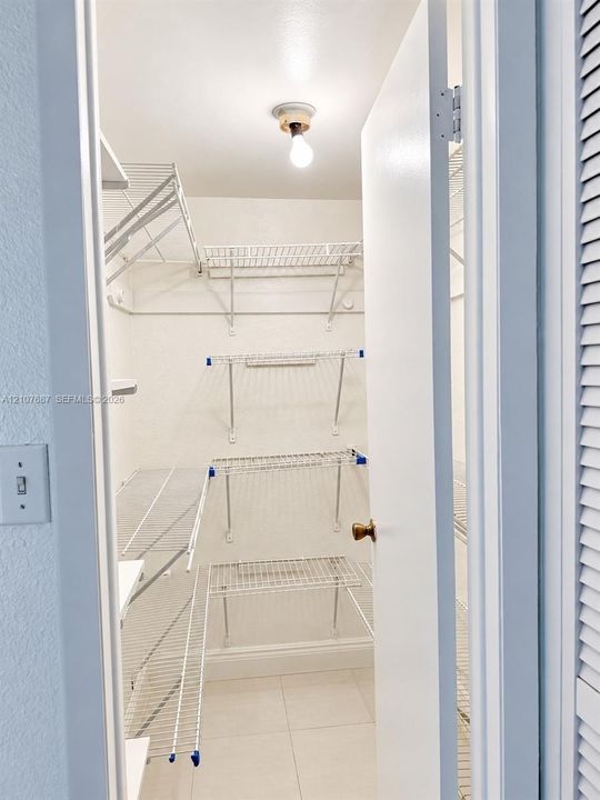 Storage area featuring white wire shelving units and tiled flooring