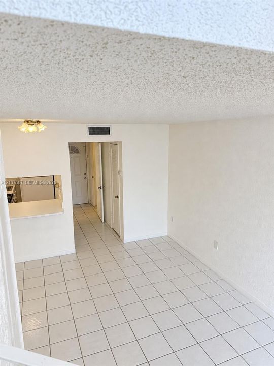 Open-concept floor plan featuring tile flooring, a pass-through service window, and a flush-mount ceiling fixture