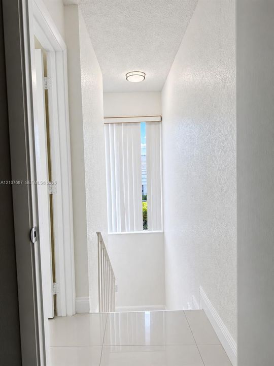 Neutral-toned tile flooring, textured wall finish, and a flush-mount circular ceiling light fixture