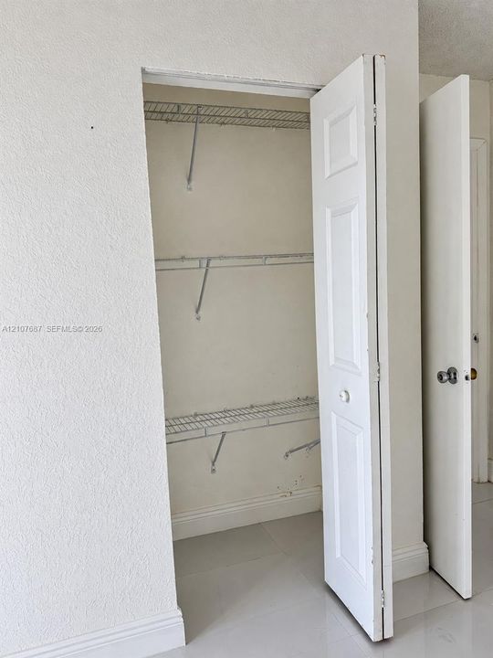 Storage closet featuring bi-fold doors and three-tier wire shelving