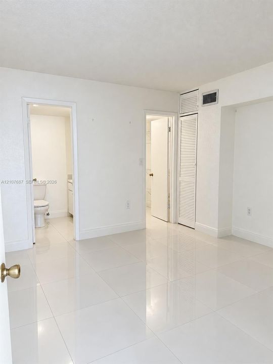 Polished tile flooring, neutral wall finishes, and floor-to-ceiling louvered closet doors