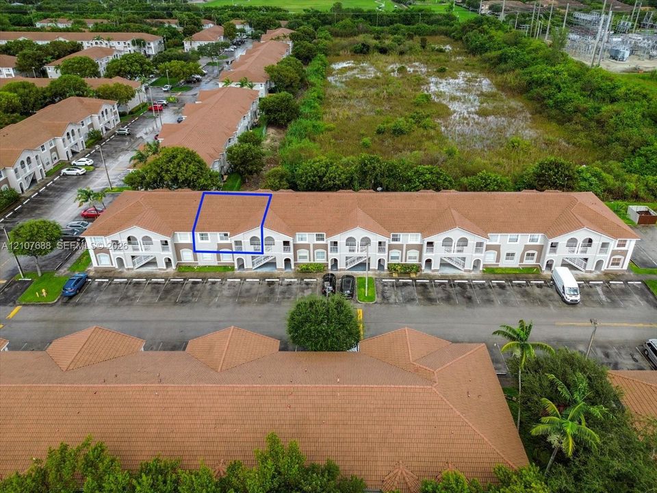 Multi-story building with a terracotta-toned tile roof and arched architectural detailing, featuring dedicated asphalt parking and professional landscaping