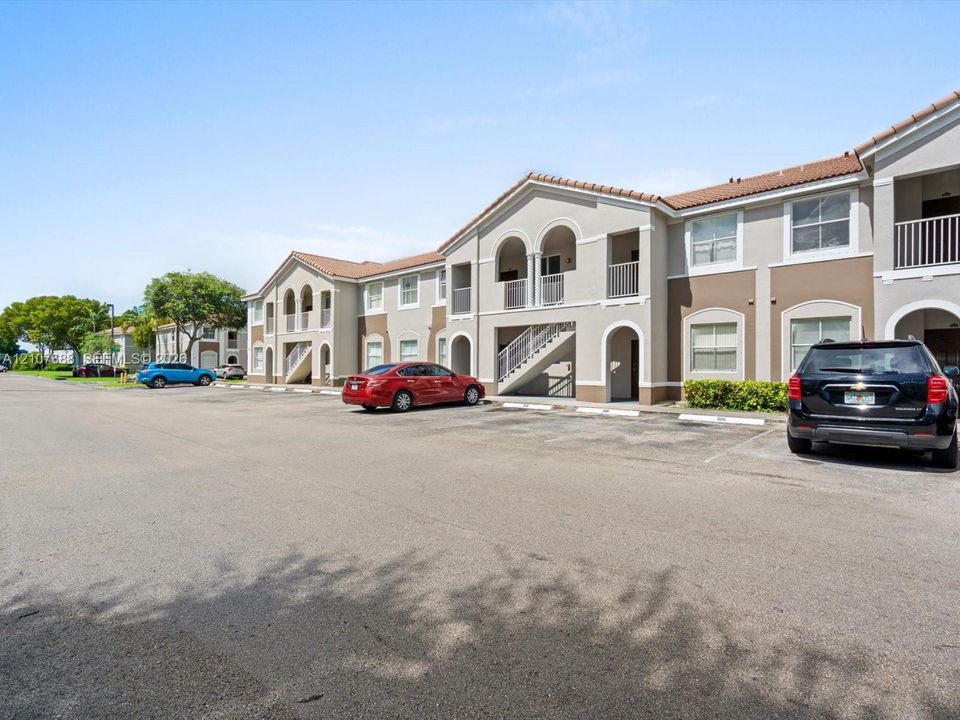 Multi-story exterior featuring a stucco facade, arched architectural detailing, tile roofing, and private balconies with metal railings