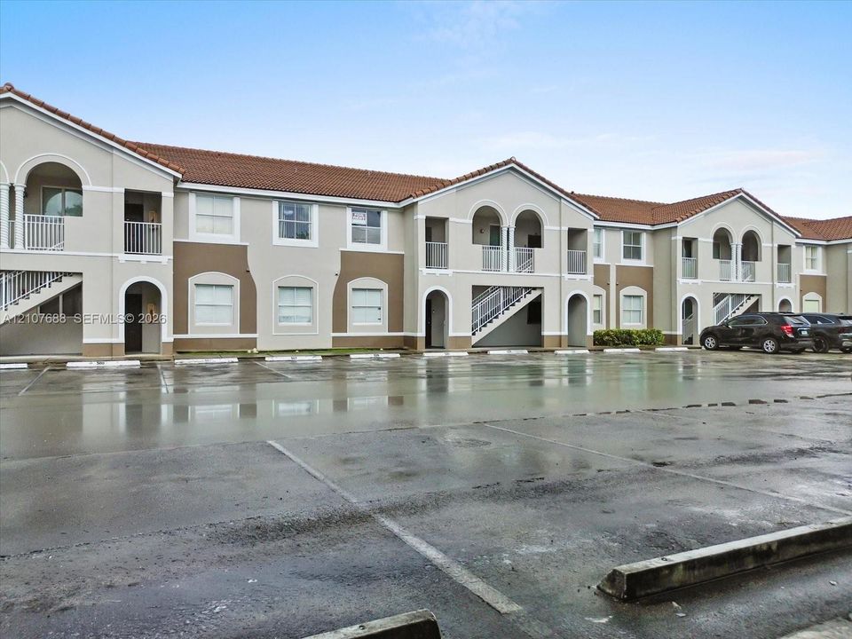 Multi-story exterior featuring a tile roof, stucco facade, arched architectural details, and private balconies with metal railings