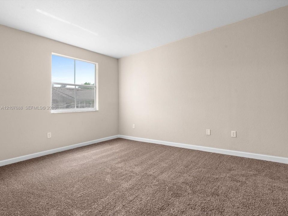 Neutral-toned walls, wall-to-wall carpeting, and a single-hung window