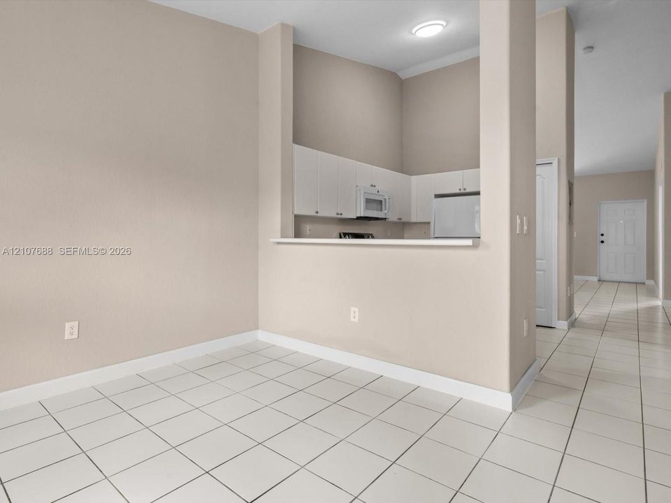 Kitchen featuring white cabinetry, an integrated microwave, and a pass-through counter, with ceramic tile flooring throughout