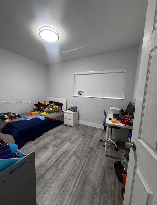 Room featuring wood-finish flooring, a horizontal slider window with integrated roller shade, and a flush-mount circular ceiling light fixture