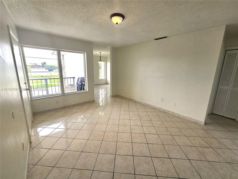 Large-format tile flooring, oversized picture window, and built-in closet with louvered doors