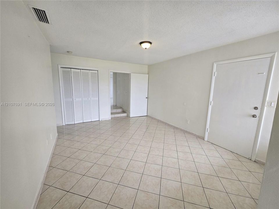 Neutral-toned ceramic tile flooring, bifold closet doors, and flush-mount lighting fixture