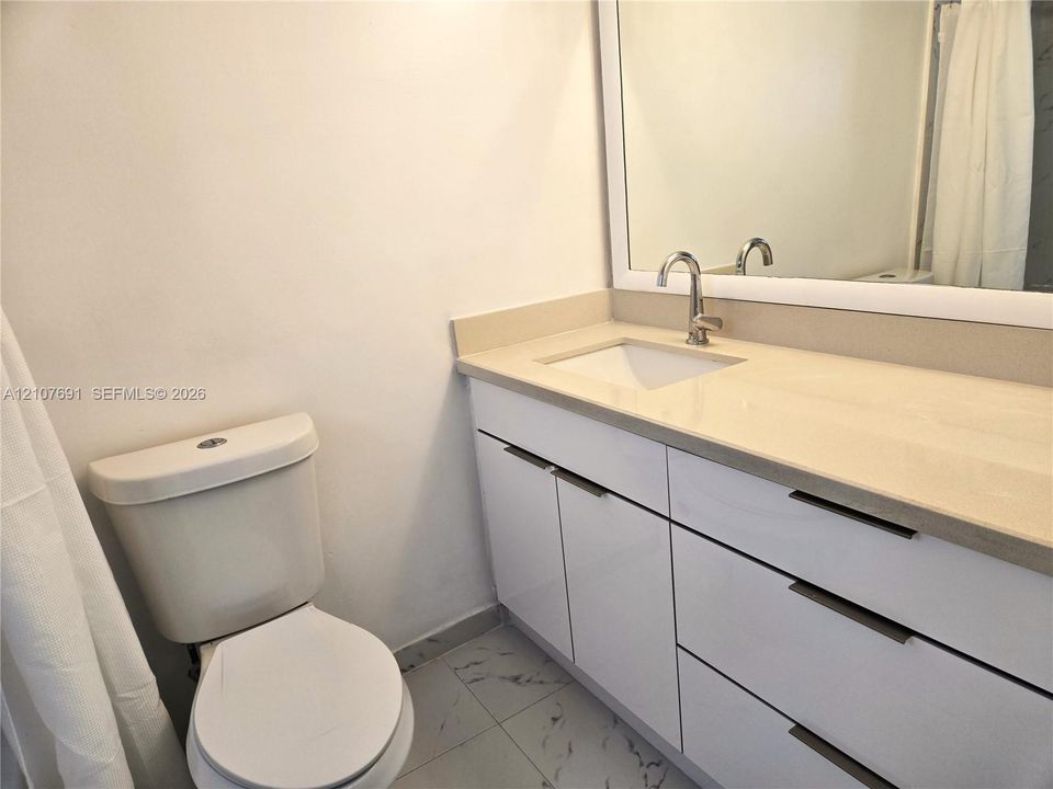 Modern bathroom vanity featuring white cabinetry, integrated stone-finish countertop with an undermount sink, high-arc polished chrome faucet, and expansive wall-mounted mirror