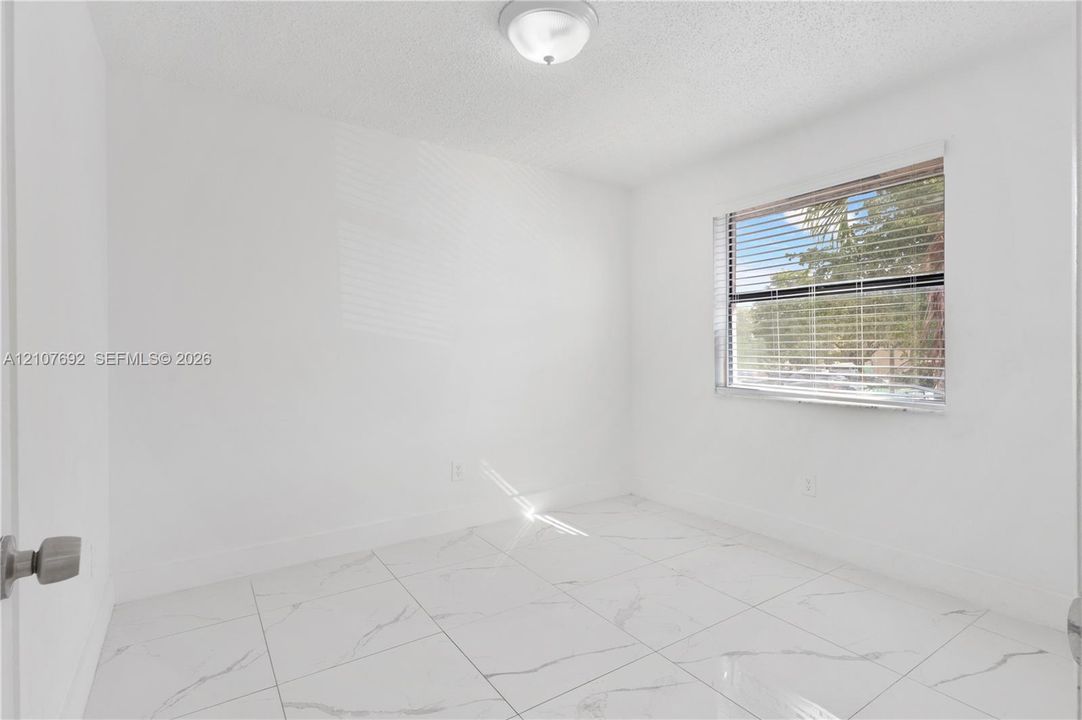 Interior room featuring large-format tile flooring with marble-pattern veining, a single-hung window with horizontal blinds, and a flush-mount dome light fixture