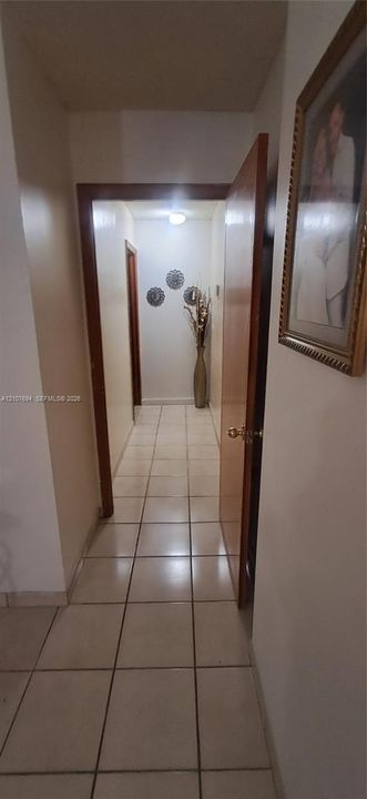 Hallway featuring large-format ceramic tile flooring, solid wood-finish door frames, and a flush-mount ceiling light fixture
