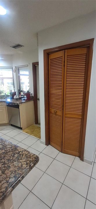 Kitchen featuring louvered wood-finish closet doors, stone-surface countertops, and ceramic tile flooring